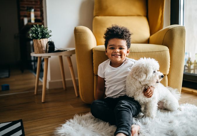 Child sits on the floor with a white dog