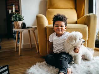 Child sits on the floor with a white dog