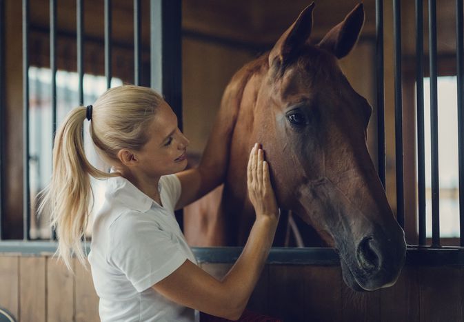 Woman with horse in stall.