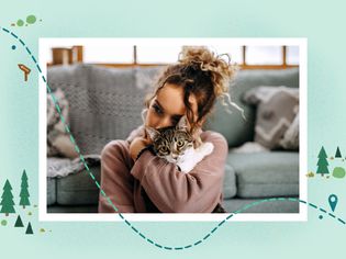 woman wearing a brown sweater cuddles tabby cat