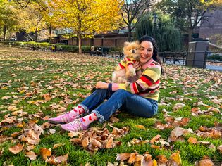 Woman with small dog wearing matching sweaters in a park