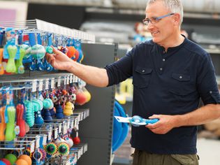 middle-aged man picks out dog toys at pet store