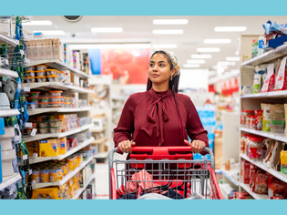 Woman shopping in a pet supply store pushing a cart near dog food products on shelves